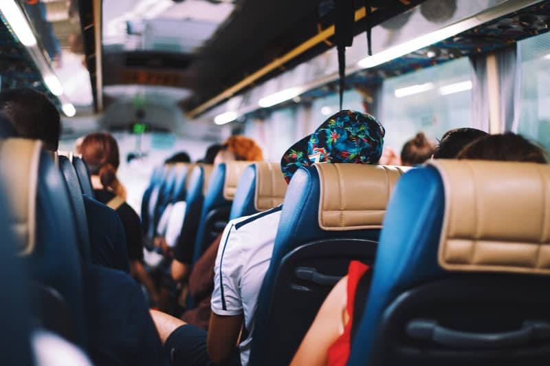 Pessoas sentadas em um ônibus de viagem vistas de costas