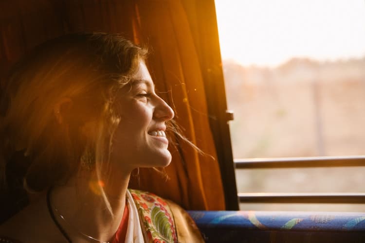 Mulher sorridente ao viajar de ônibus pela Europa