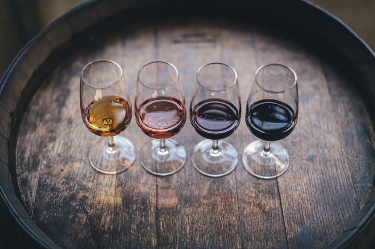 Quatro taças de vinhos portugueses lado a lado sobre um barril